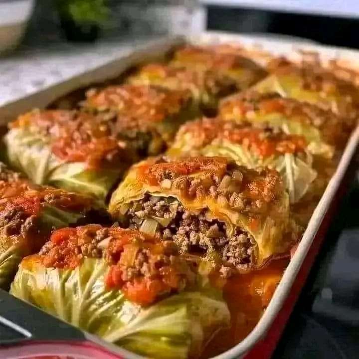 Stuffed cabbage rolls in a rich tomato sauce, garnished with fresh dill and served on a plate.