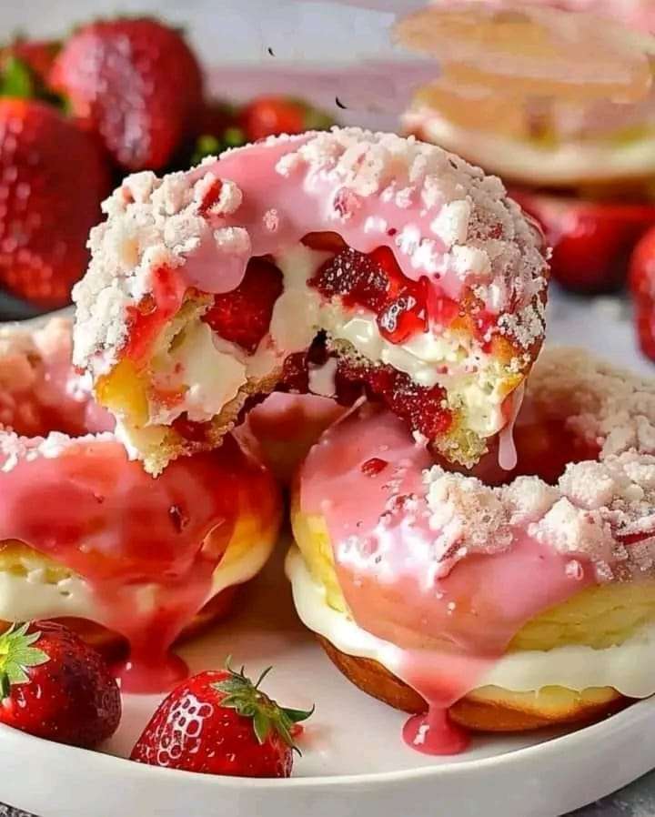 Strawberry cheesecake stuffed donuts drizzled with glaze, garnished with fresh strawberries.