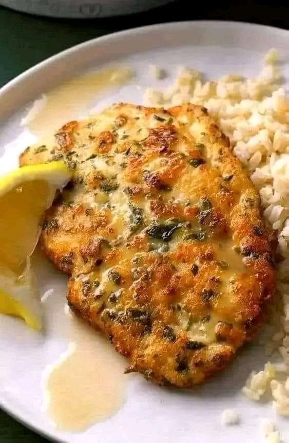 A plate of Chicken Piccata with Lemon Sauce, garnished with parsley and lemon slices, served with pasta and vegetables.