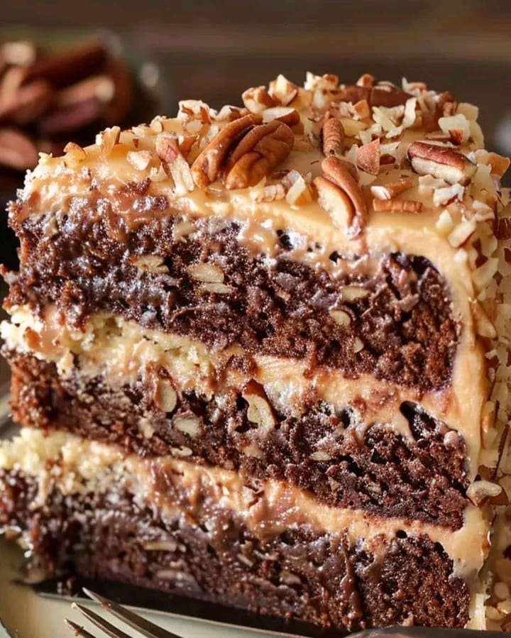 A beautifully layered German chocolate cake with creamy coconut-pecan frosting, served on a rustic plate.