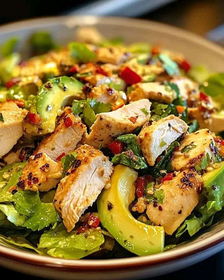 A fresh bowl of Avocado Chicken Salad with shredded chicken, diced avocados, cherry tomatoes, and lime dressing.