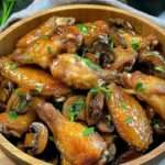 A plate of golden chicken wings with sautéed mushrooms garnished with fresh parsley.