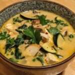 Creamy Thai Zucchini Coconut Soup served with fresh cilantro leaves and a dollop of yogurt.