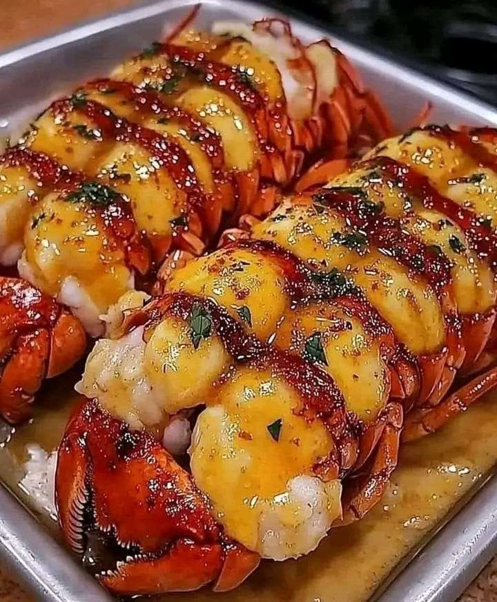 Garlic butter lobster tail with lemon wedges and fresh parsley, baked to perfection.