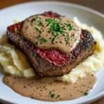 Filet mignon steaks served with creamy peppercorn sauce and garnished with fresh parsley.