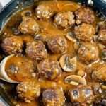 A plate of gourmet meatballs in a creamy mushroom sauce garnished with fresh parsley.