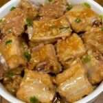 A plate of Garlic Steamed Pork Ribs garnished with green onions, served with steamed rice.