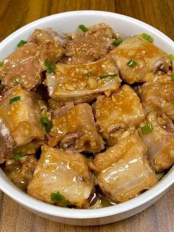 A plate of Garlic Steamed Pork Ribs garnished with green onions, served with steamed rice.