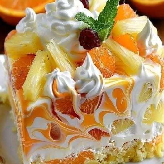 A refreshing No Bake Orange Pineapple Swirl Cheesecake topped with whipped cream, pineapple chunks, mandarin orange slices, and fresh mint leaves for garnish.