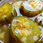 A jar of vibrant Fire and Ice Pickles with cucumbers, carrots, and red pepper flakes, garnished with fresh dill.