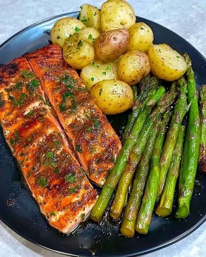 Garlic Herb Salmon served with roasted potatoes and sautéed asparagus, garnished with fresh parsley on a plate.