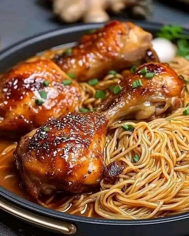 Roasted chicken served with noodles in savory sauce, garnished with green onions.