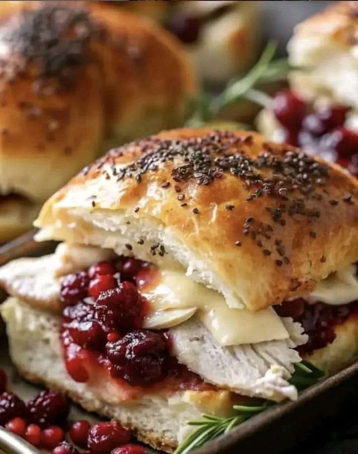 A platter of golden Baked Cranberry Turkey Sliders with gooey Havarti cheese and cranberry sauce.