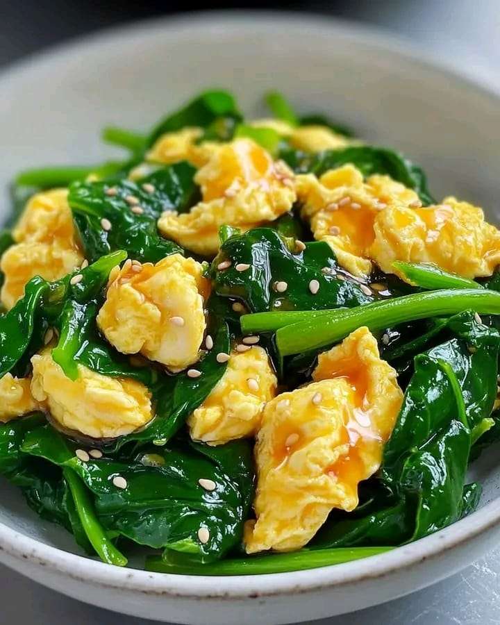 A plate of vibrant Spinach and Egg Stir-Fry garnished with sesame seeds and green onions.