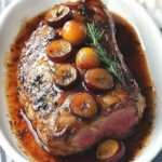 Plum-Glazed Lamb leg roasted to perfection, garnished with rosemary and served with plum sauce.