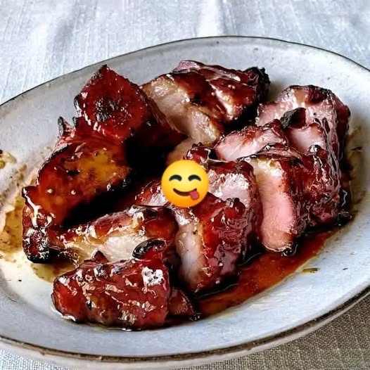 Glazed Char Siu pork sliced on a cutting board with a shiny red glaze.