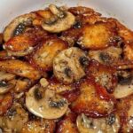 Glazed Char Siu pork sliced on a cutting board with a shiny red glaze.