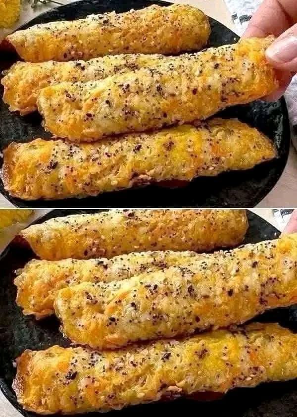 Close-up of golden brown crispy cheese rolls seasoned with black pepper and sesame seeds being held by a hand.
